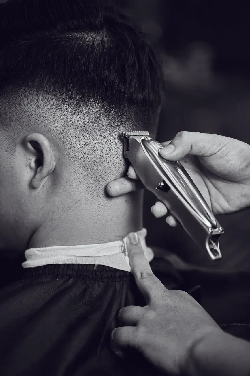 Black-and-white close-up of a clipper blending a skin fade behind the ear