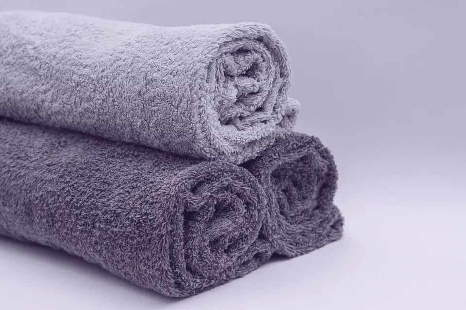 Two rolled towels stacked on a pale surface