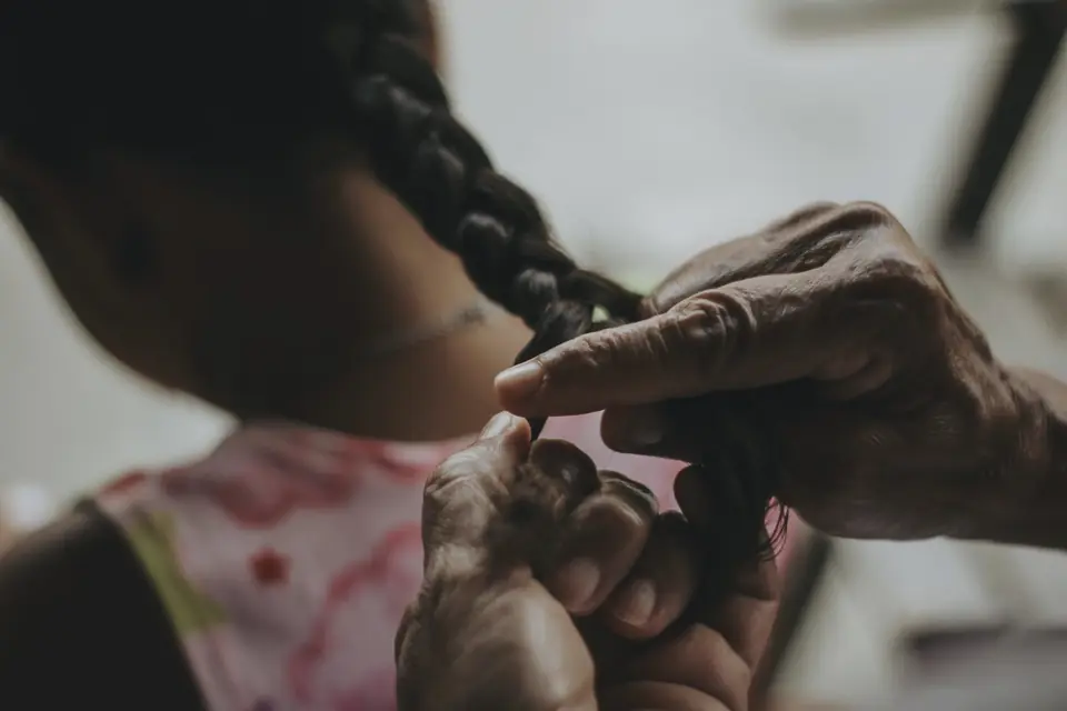 Hands plaiting a long braid close to the shoulder
