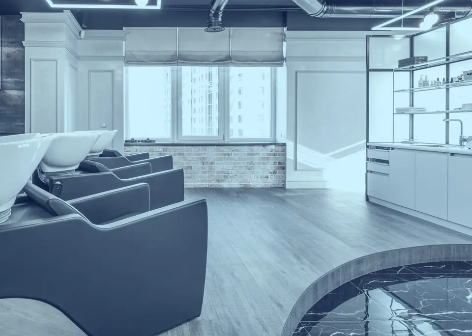 An empty salon with backwash basins and daylight from tall windows