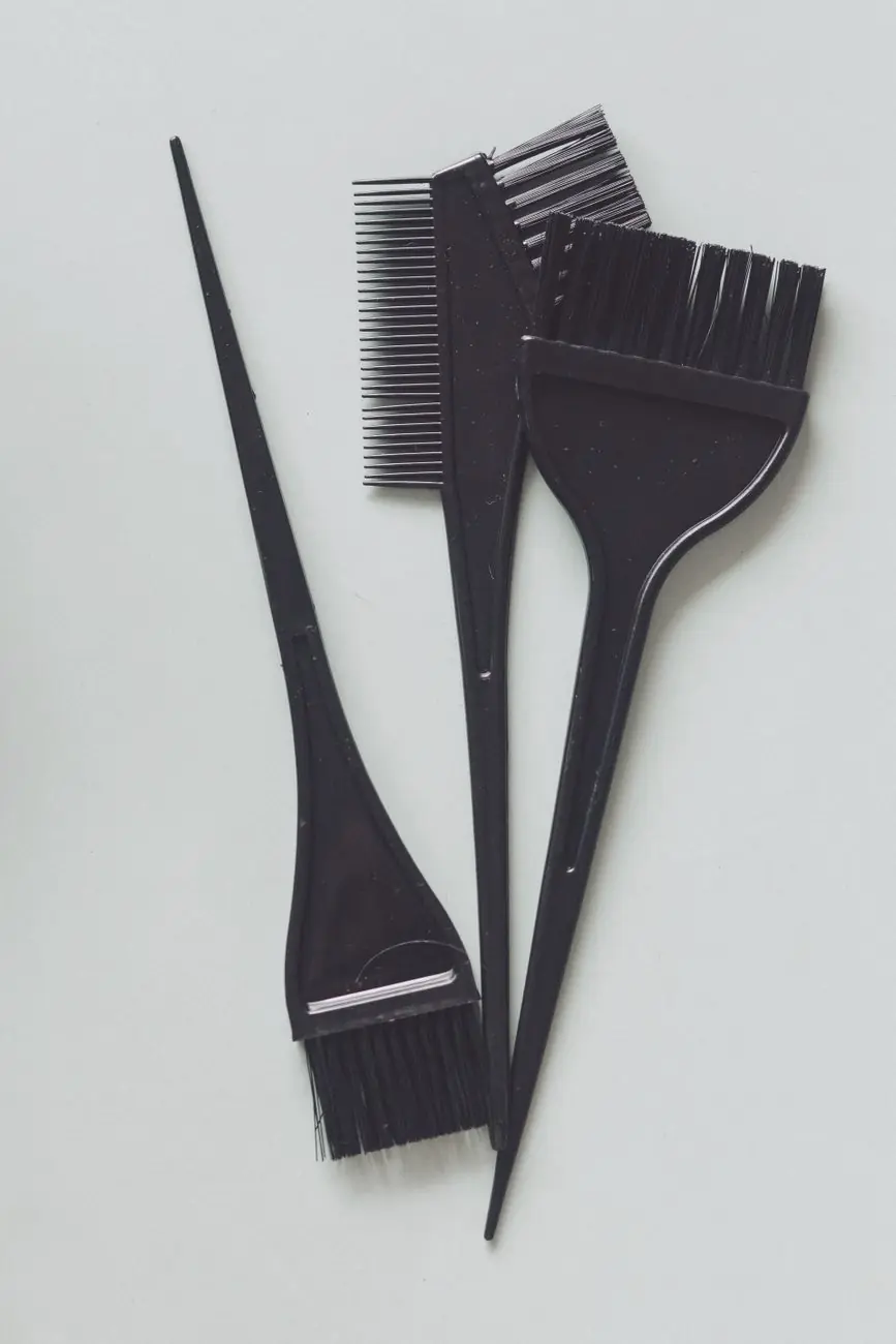 Three tint brushes and a comb laid out on a plain surface