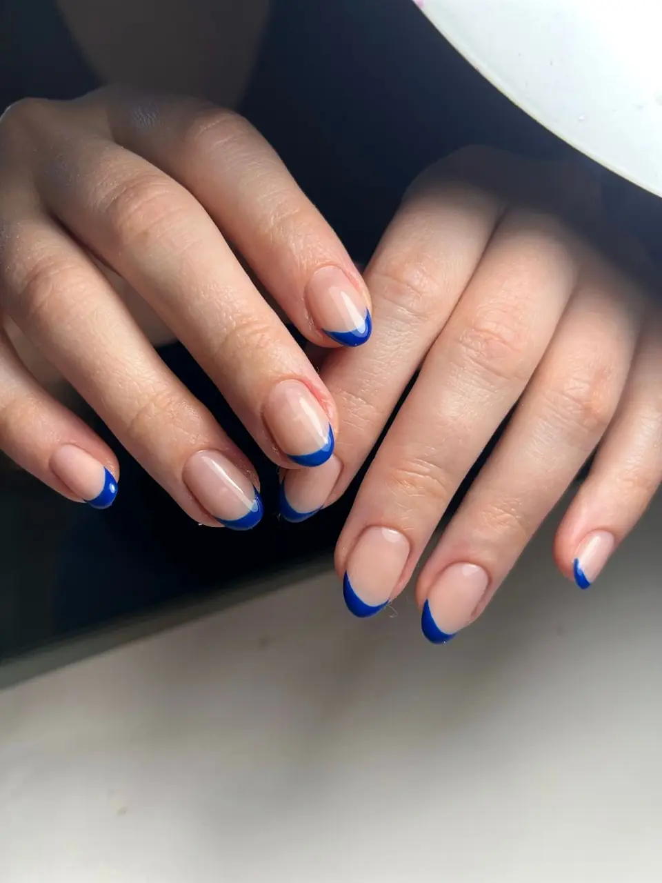 Fingertips with a fine blue French edge on a pale nail
