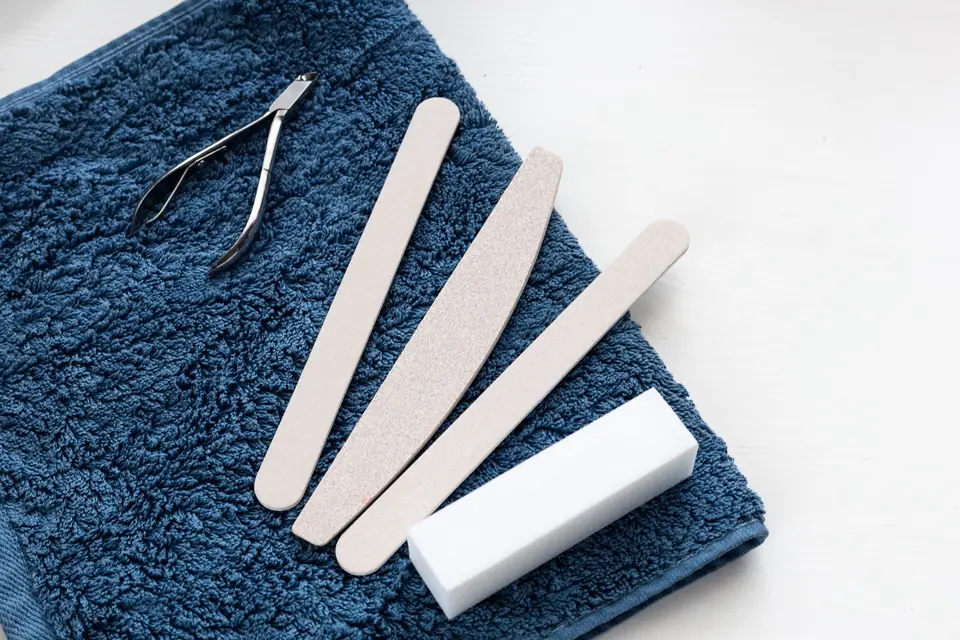 Nail files, a buffer block and cuticle nippers laid on a blue towel